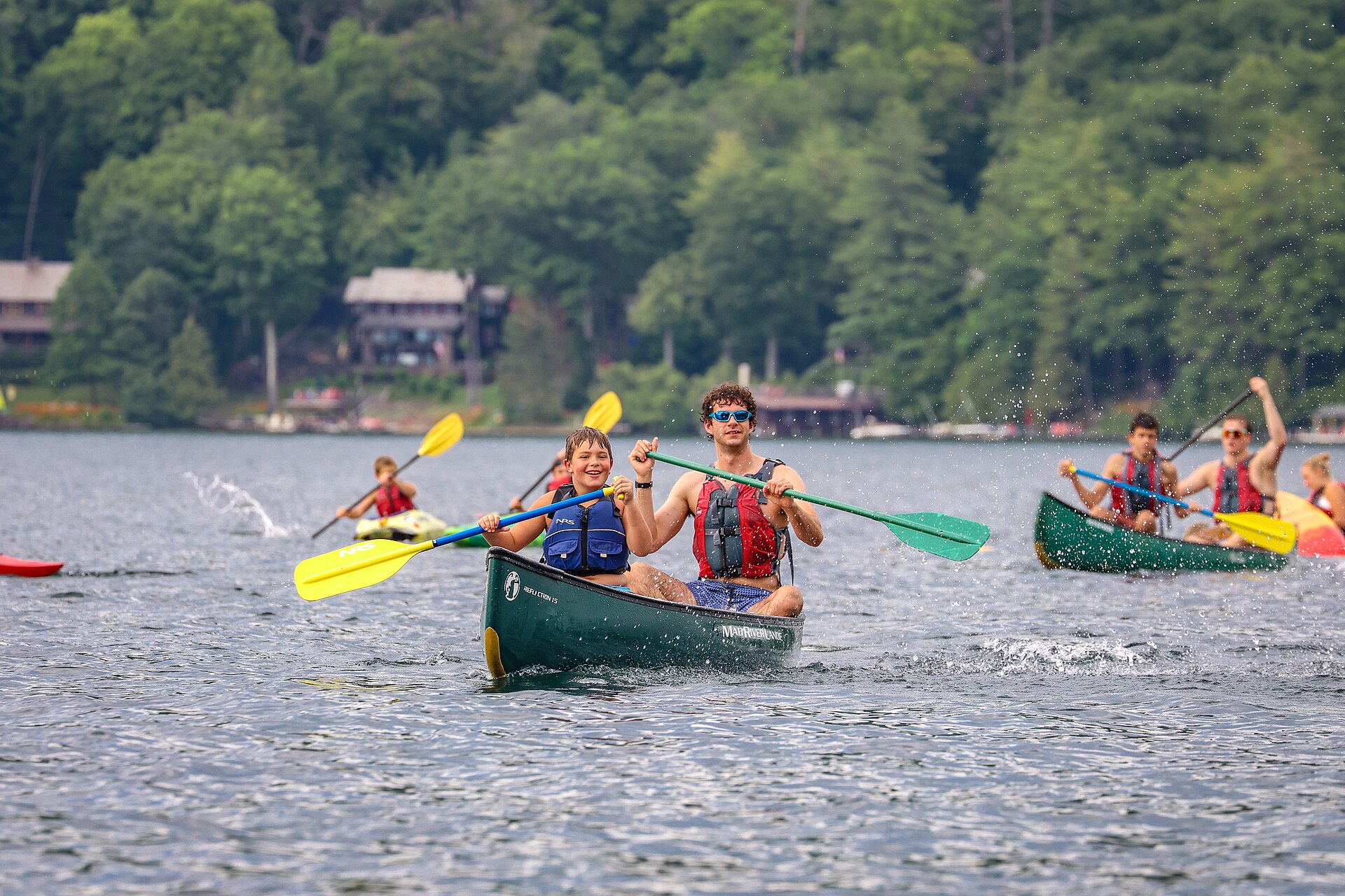 Camp counselor and camper paddling a canoe on a summer lake